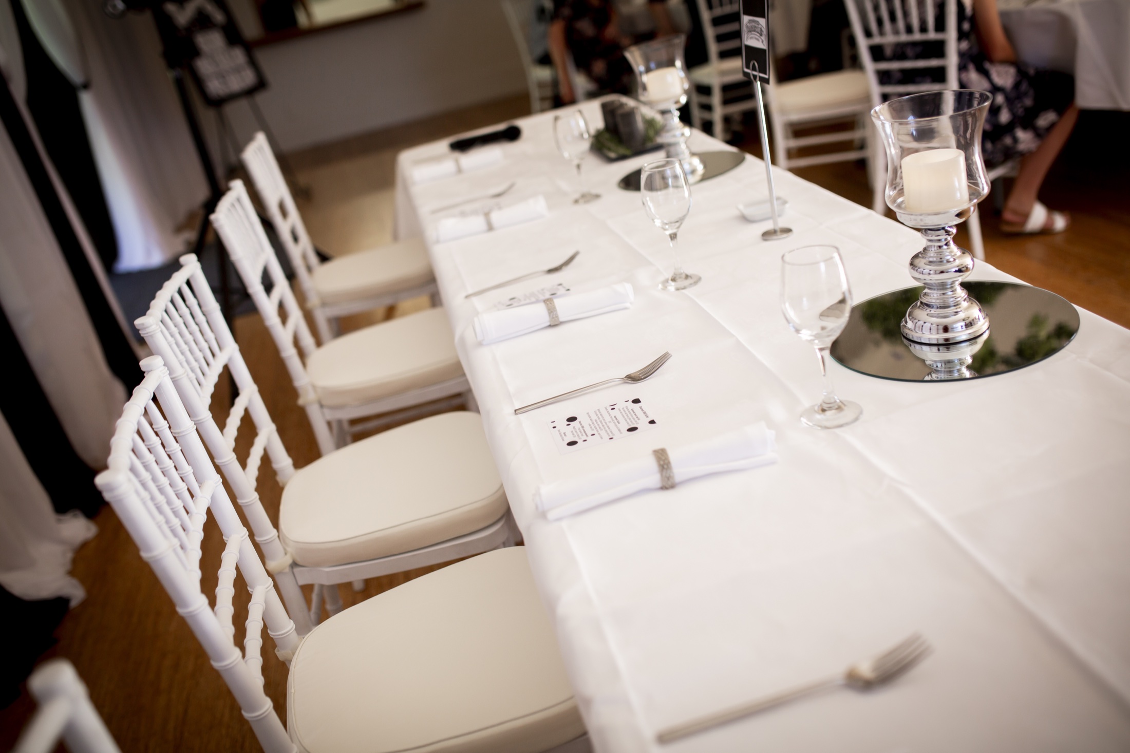 White reception table with glassware and Chiavari chairs